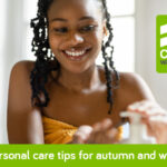 7 Personal Care Tips for Great Looking Skin This Autumn & Winter African lady in shower with towel around waist, promoting shower gel.