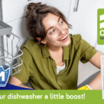 JIM™Auto Dish Salt: Give your dishwasher a little boost! Smiling lady next to open dishwasher with JIM™ Auto Dish Salt bottle.