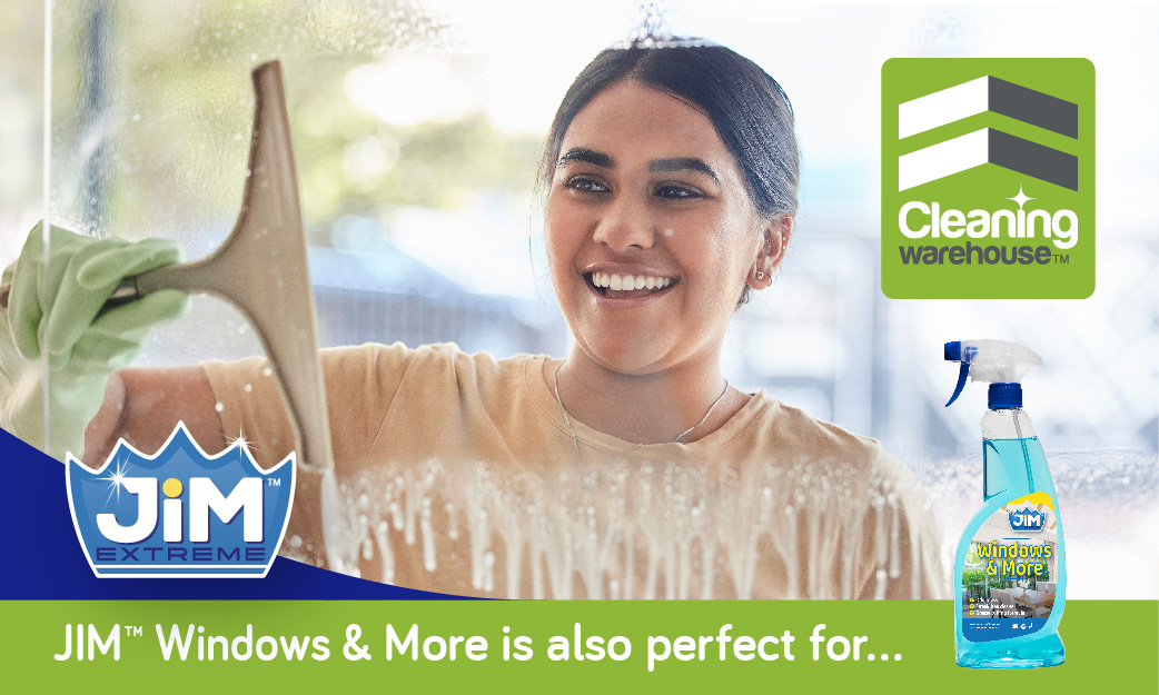 Lady smiling while cleaning a glass window with a squeegee and Window & More bottle.