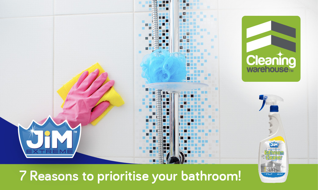 Person wearing pink glove cleaning a bathroom wall with a microfiber cloth.